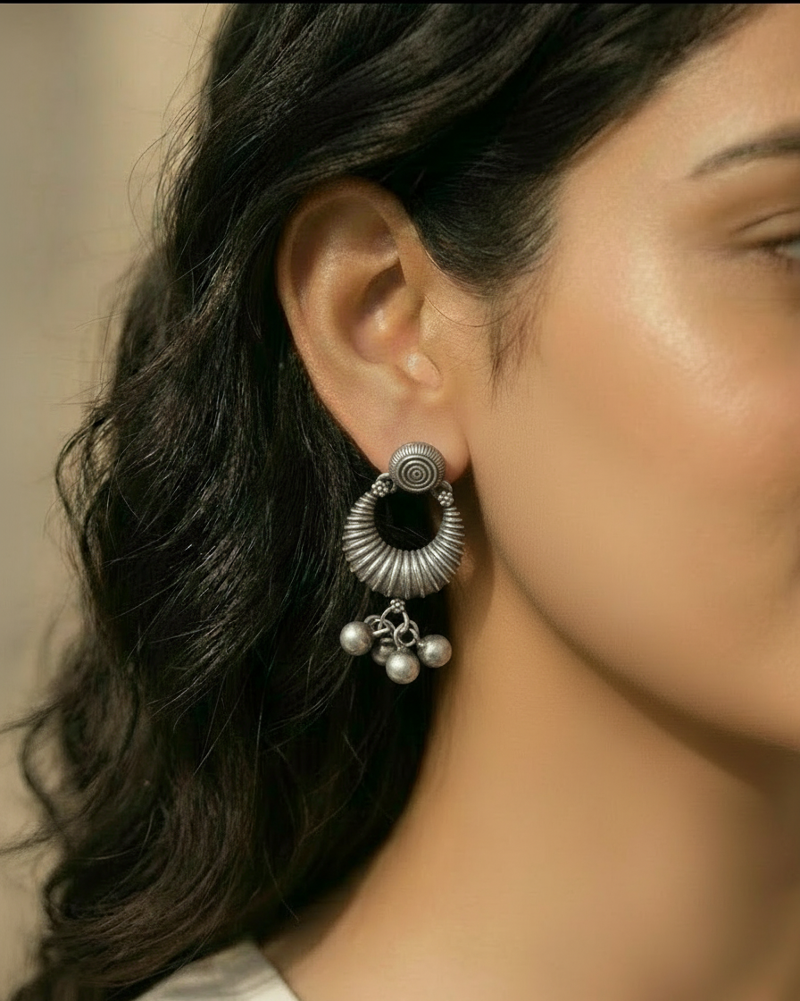 Close-up of a woman wearing a silver earring with black center and dangling beads.
