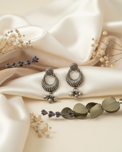 Pair of silver earrings on a soft fabric background with flowers.